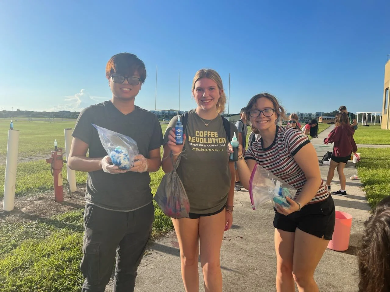 Three teens holding art supplies outside