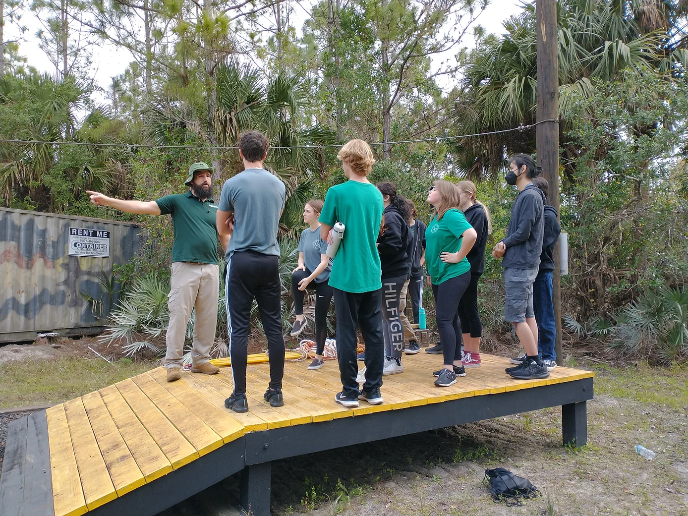 Group of students and teacher standing on a wooden structure