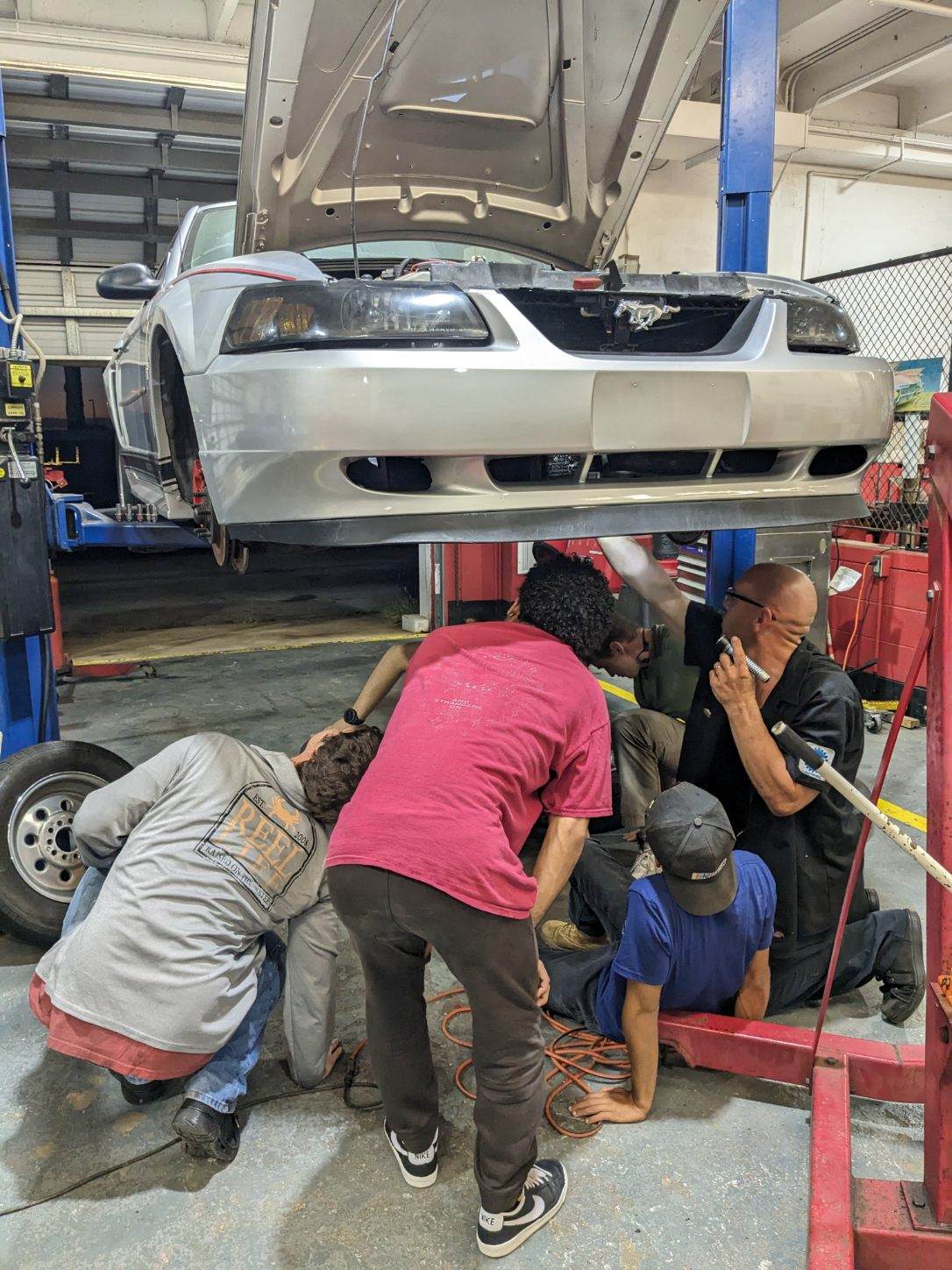 automotive students looking under a car