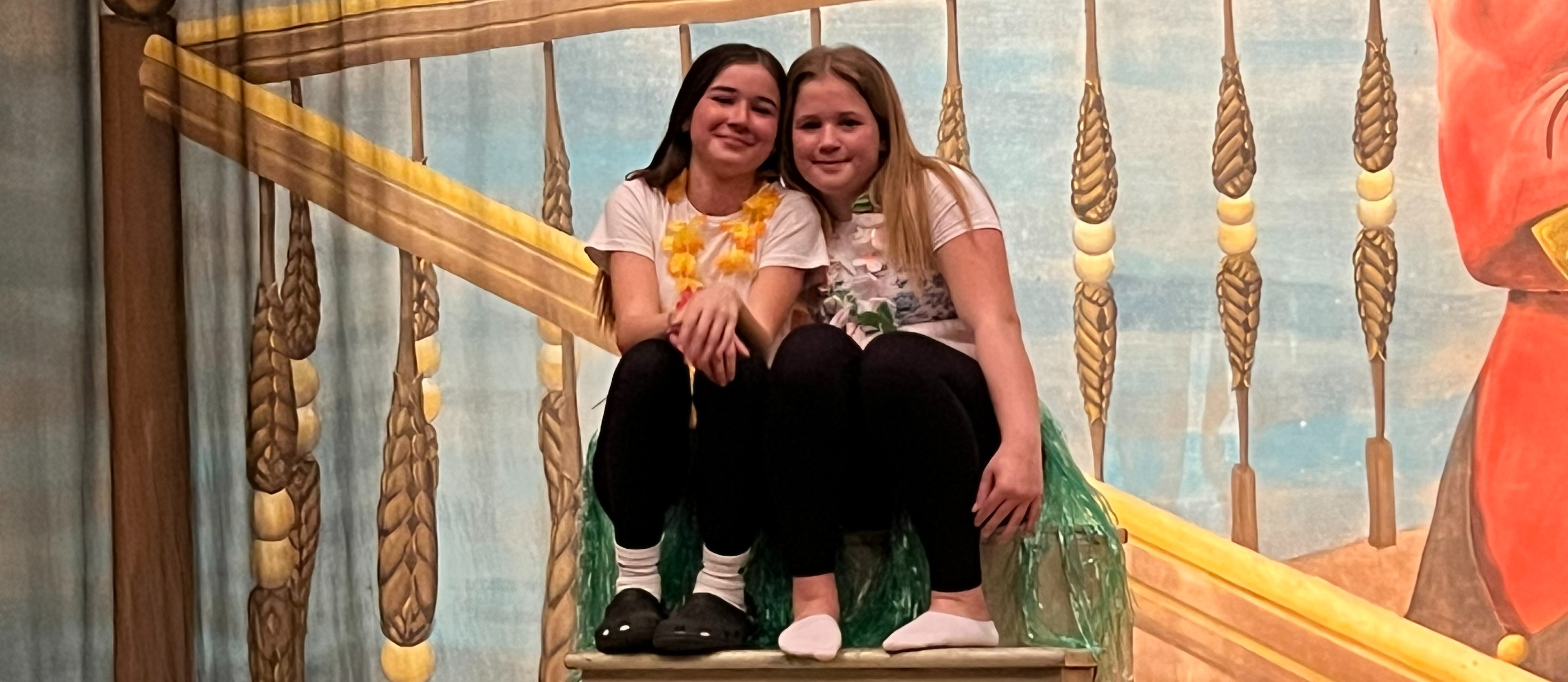 2 girls sitting together on stage
