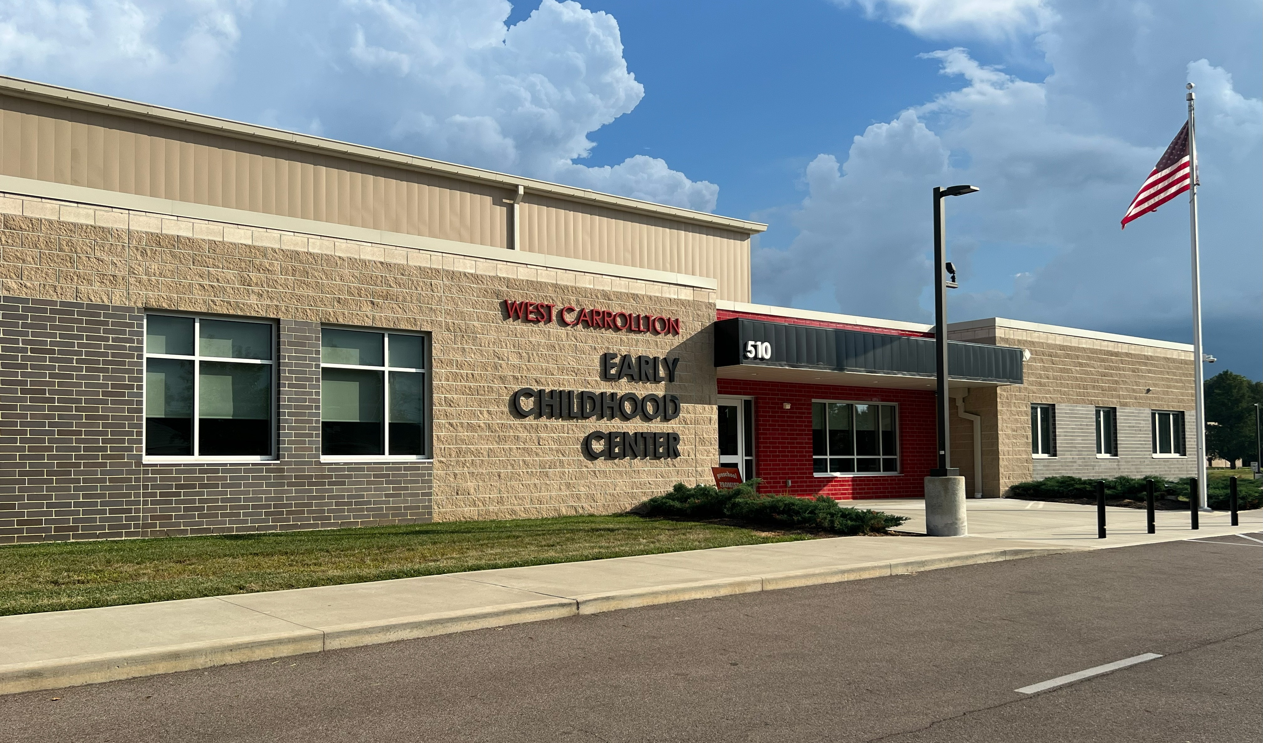 A building with brick walls and windows stands on a street. It has a red roof and "New Carbonton Early Childhood Center" text.