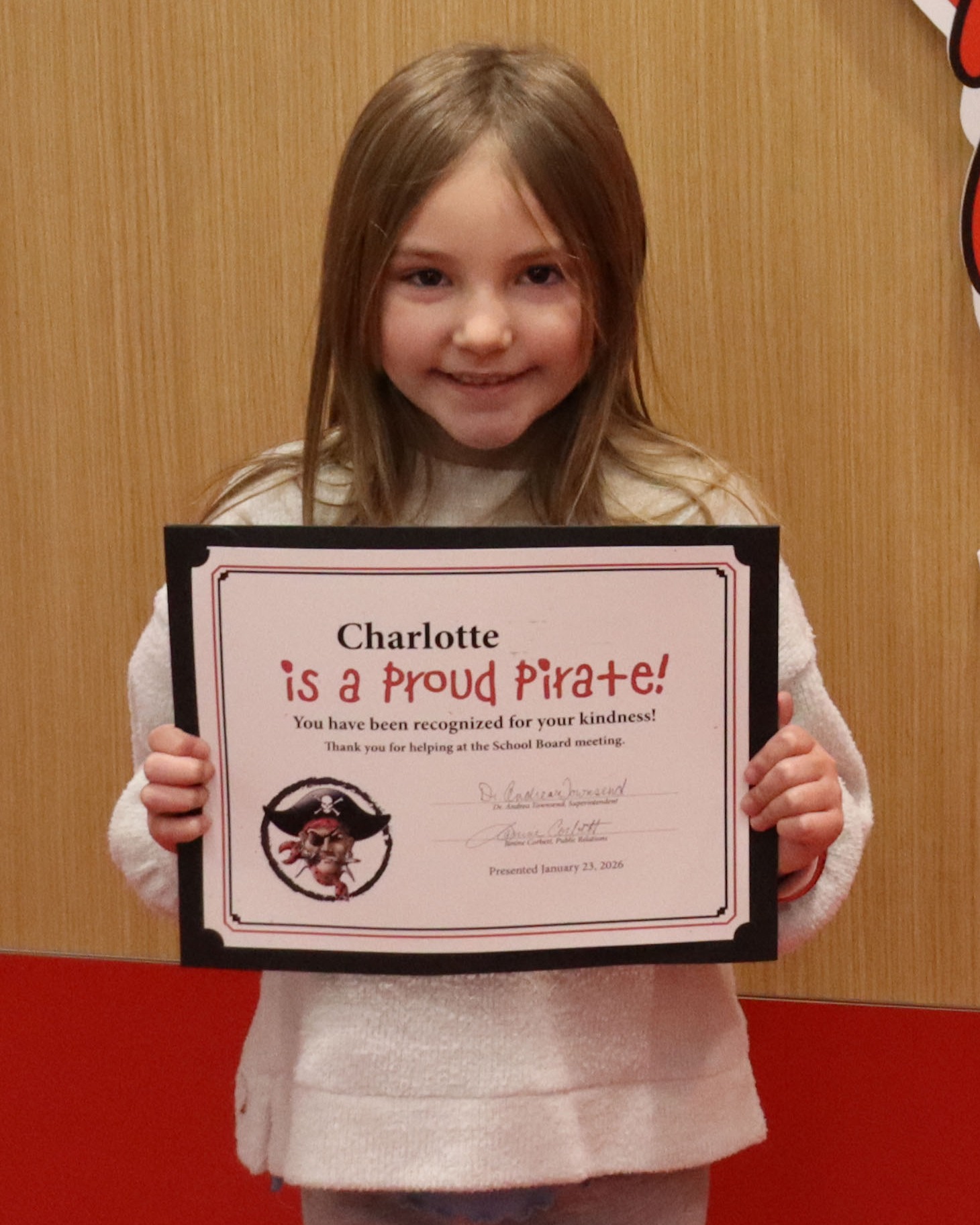 Child holding a certificate that says Proud Pirate