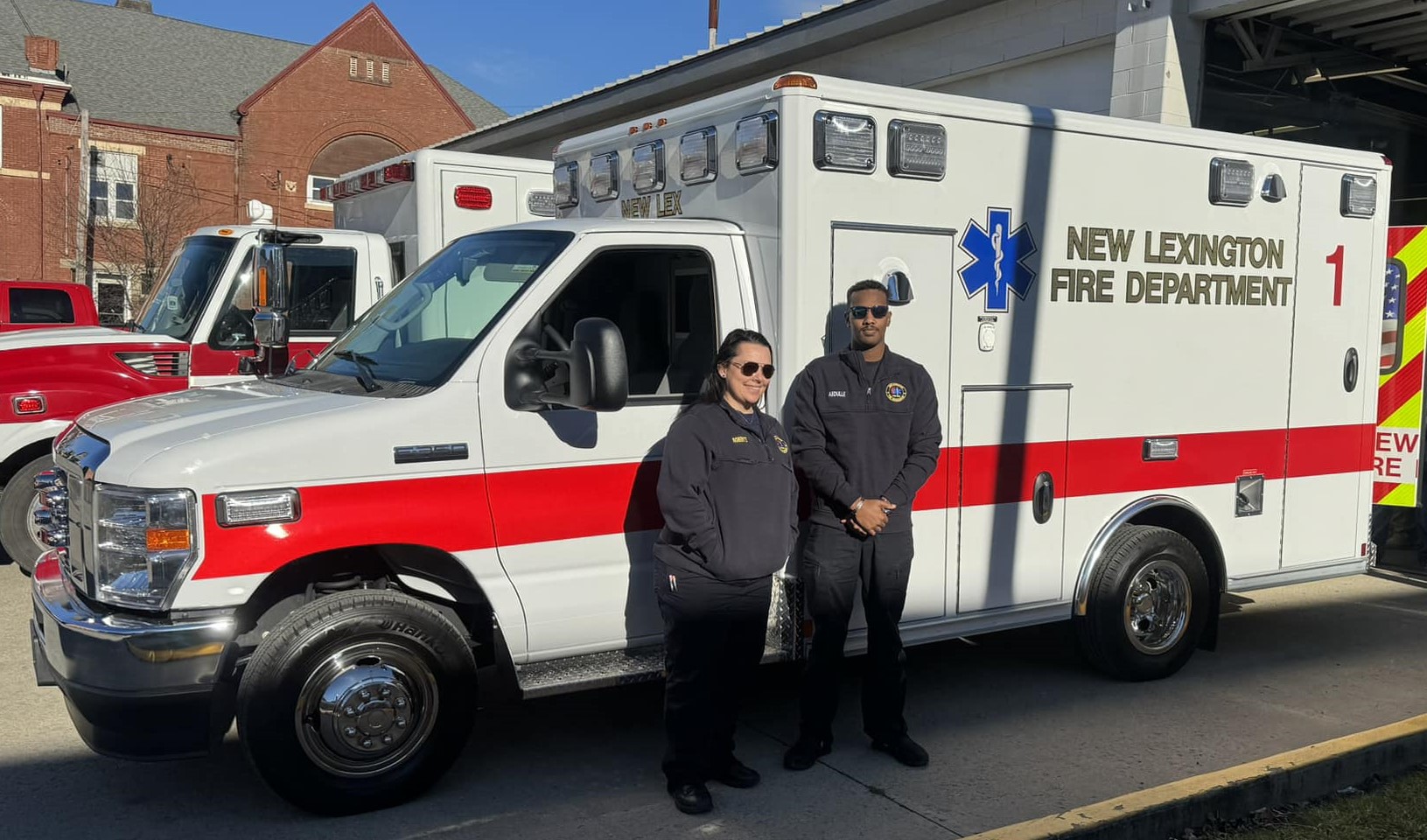 two firefighters posing in front of an ambulance