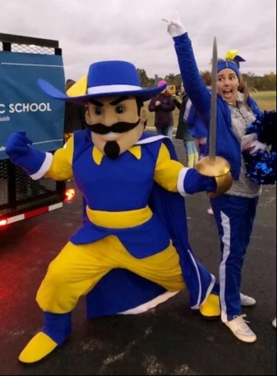 A girl wearing blue jacket and pants with a mascot