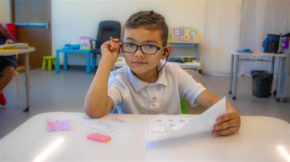 boy sitting in a chair holding a pencil
