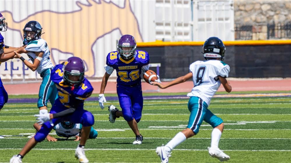 student holding a ball running down the football field