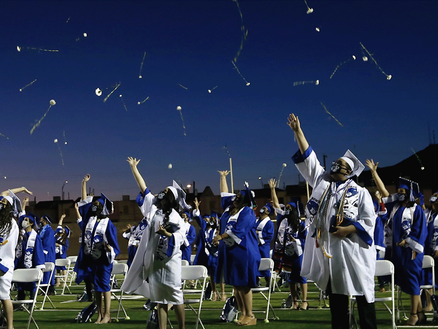 graduation caps thrown into the night sky