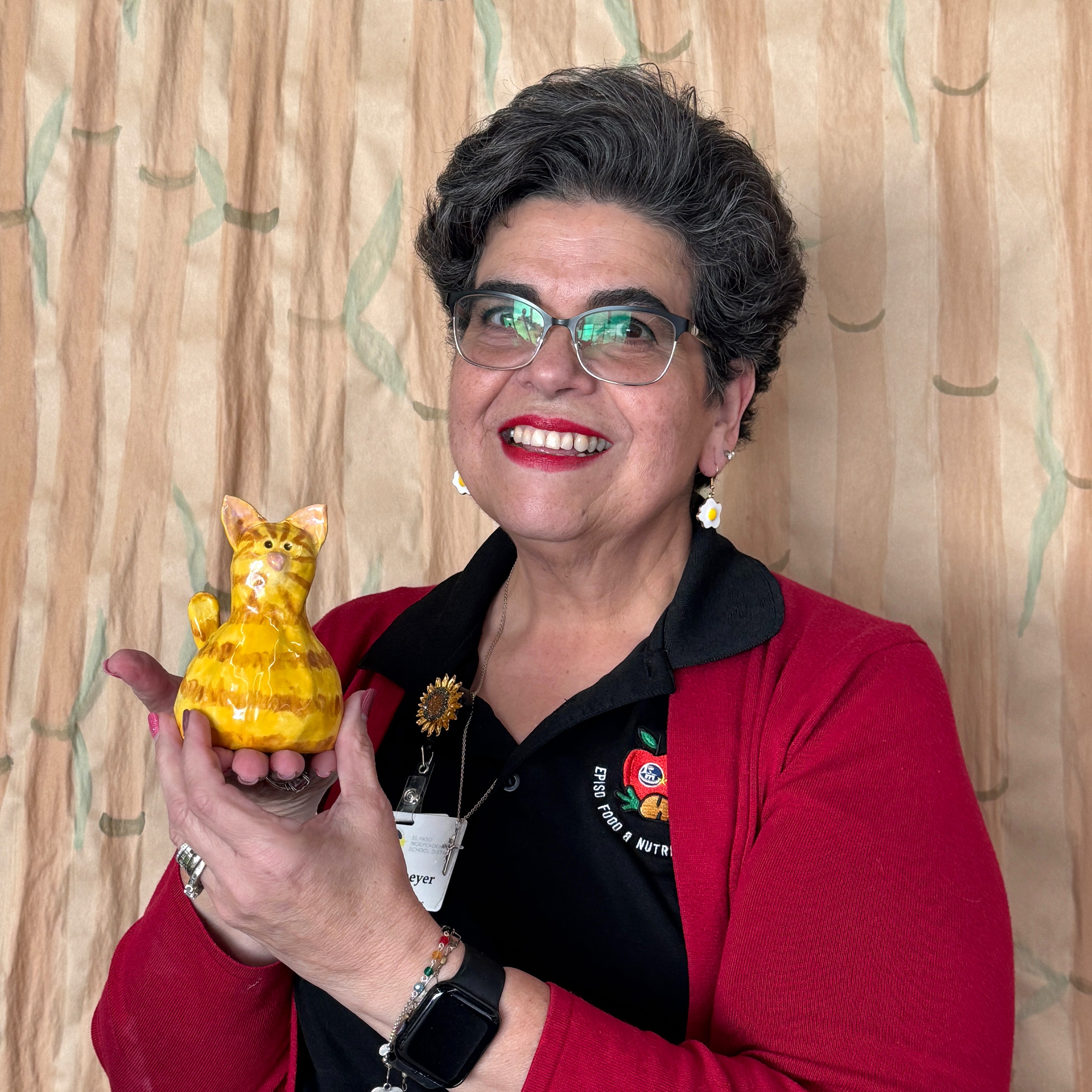 Woman smiling at camera while holding ceramic cat