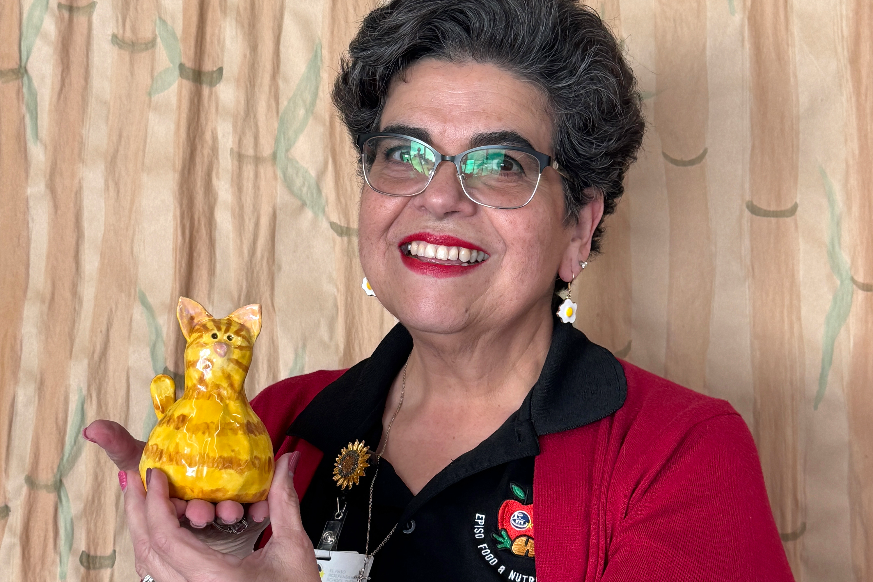 Woman smiling at camera while holding ceramic cat