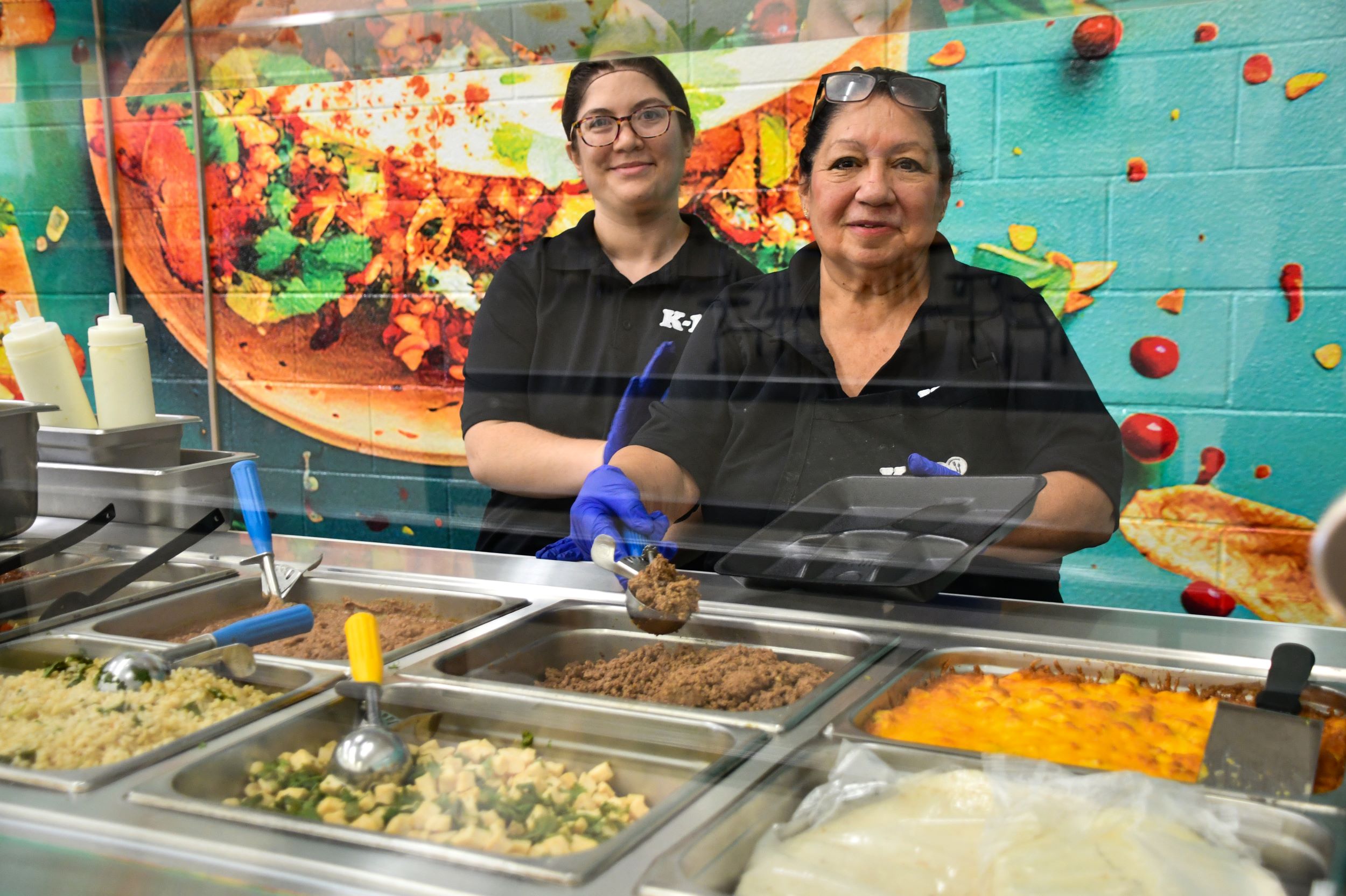 2 kitchen staff behind the street food serving line