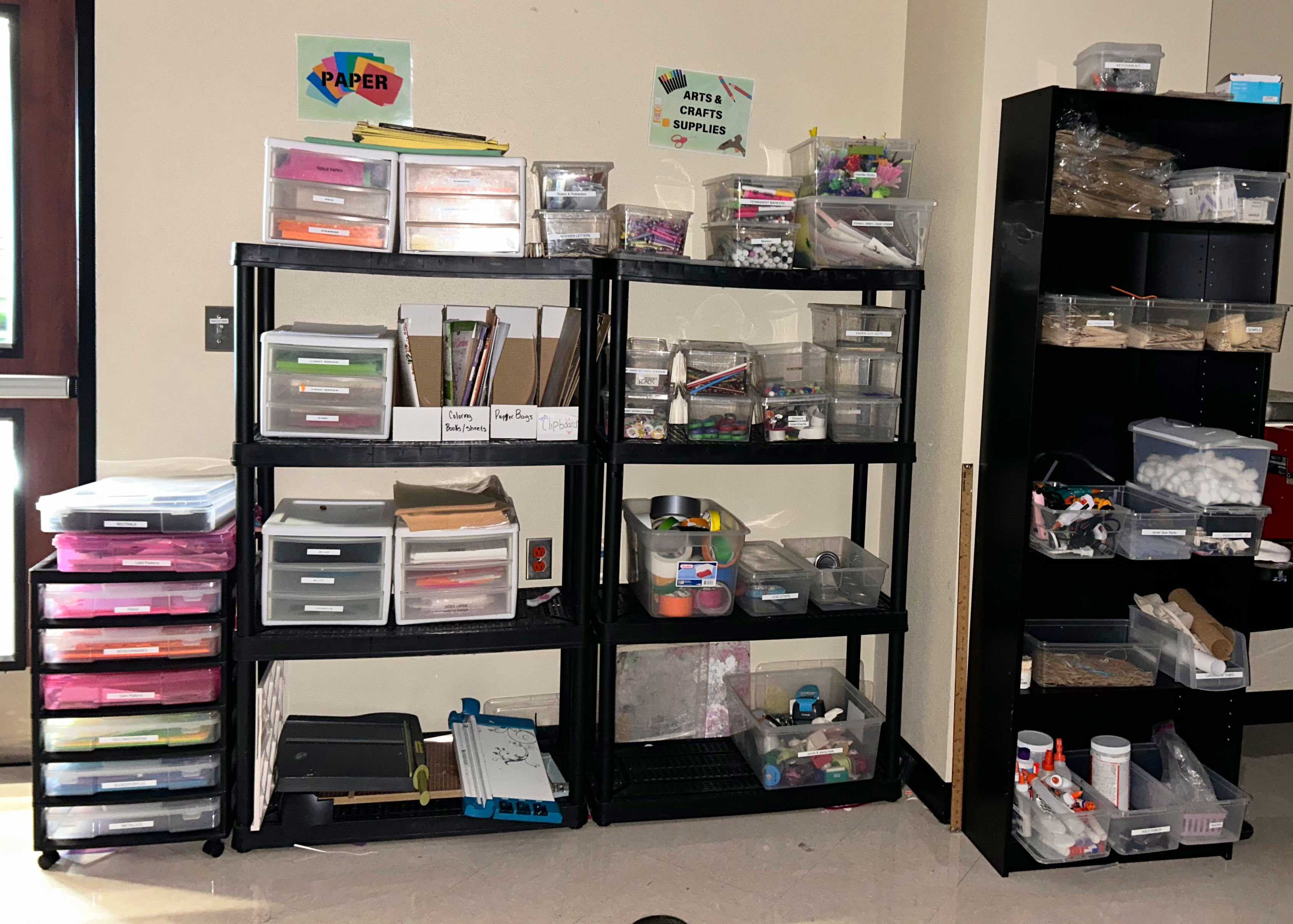Black shelves and bookshelf filled with various craft supplies.