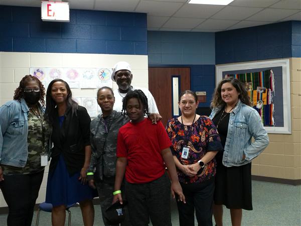 A group of people standing together in a classroom, smiling and posing for a photo.