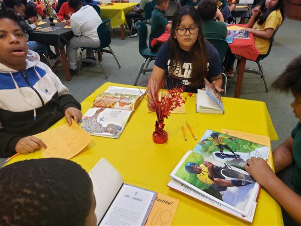 Students gathered around a table at school, engaged in discussion and studying.