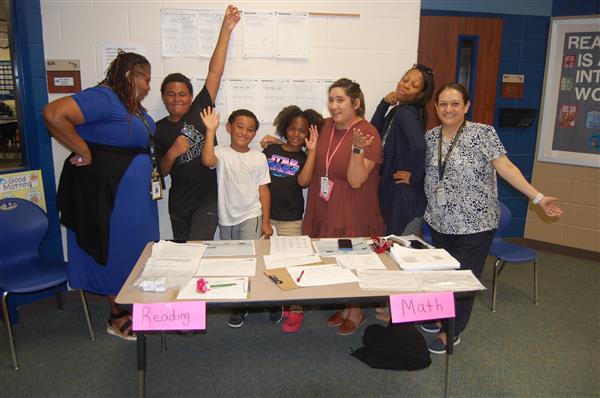 People gathered around a table in a room, smiling and posing for the camera.