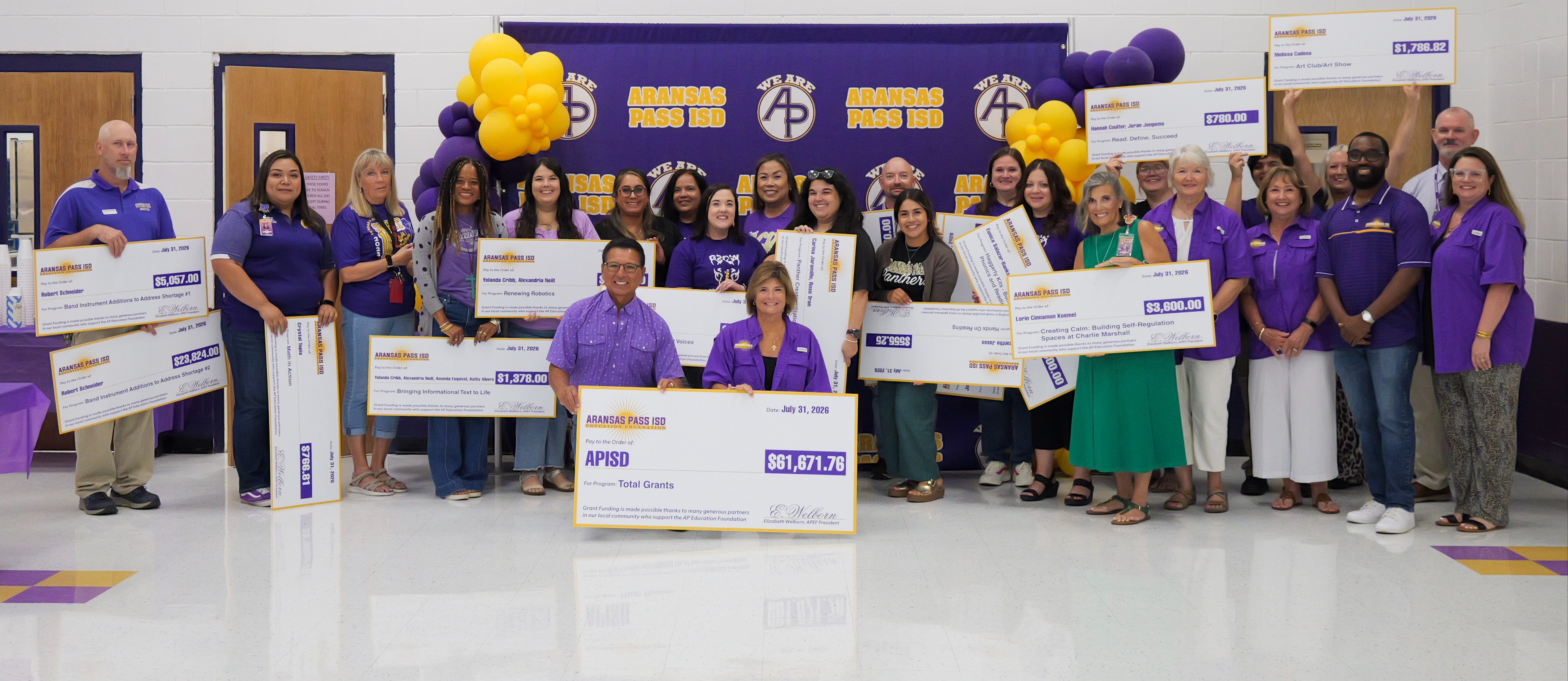 a group of teachers with large ceremonial checks in front of a purple background