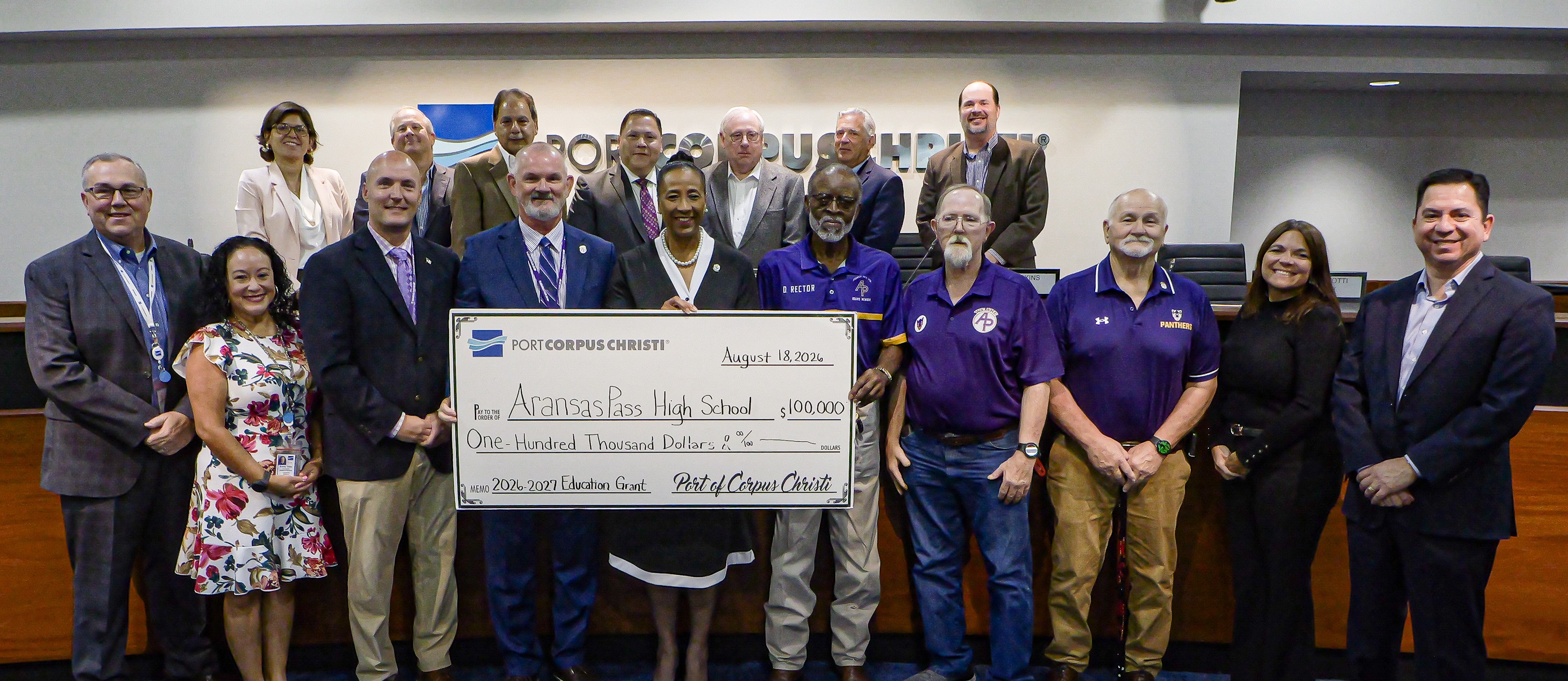 large group of people standing in front of a dais holding a ceremonial check