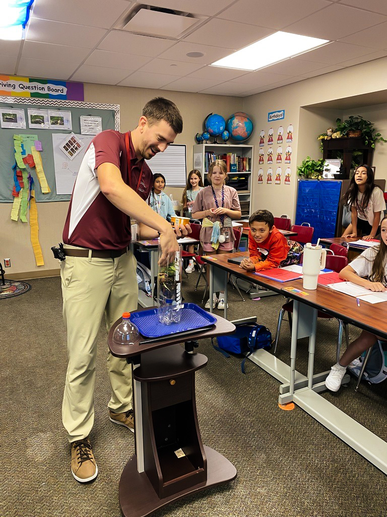 A Columbus Middle School teachers performs a science experiment in a classroom as students look on.