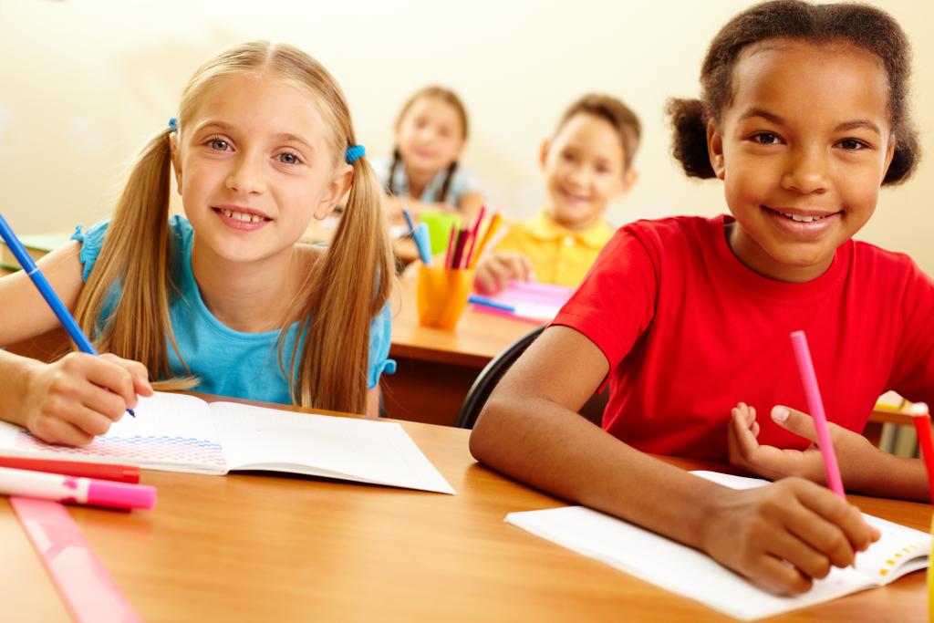 kids smiling while writing in their notebook