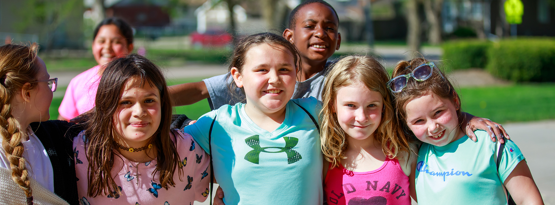 A small group of Emerson girls pose in a line for a photo, while an Emerson boy peeks his head over the girls' group.