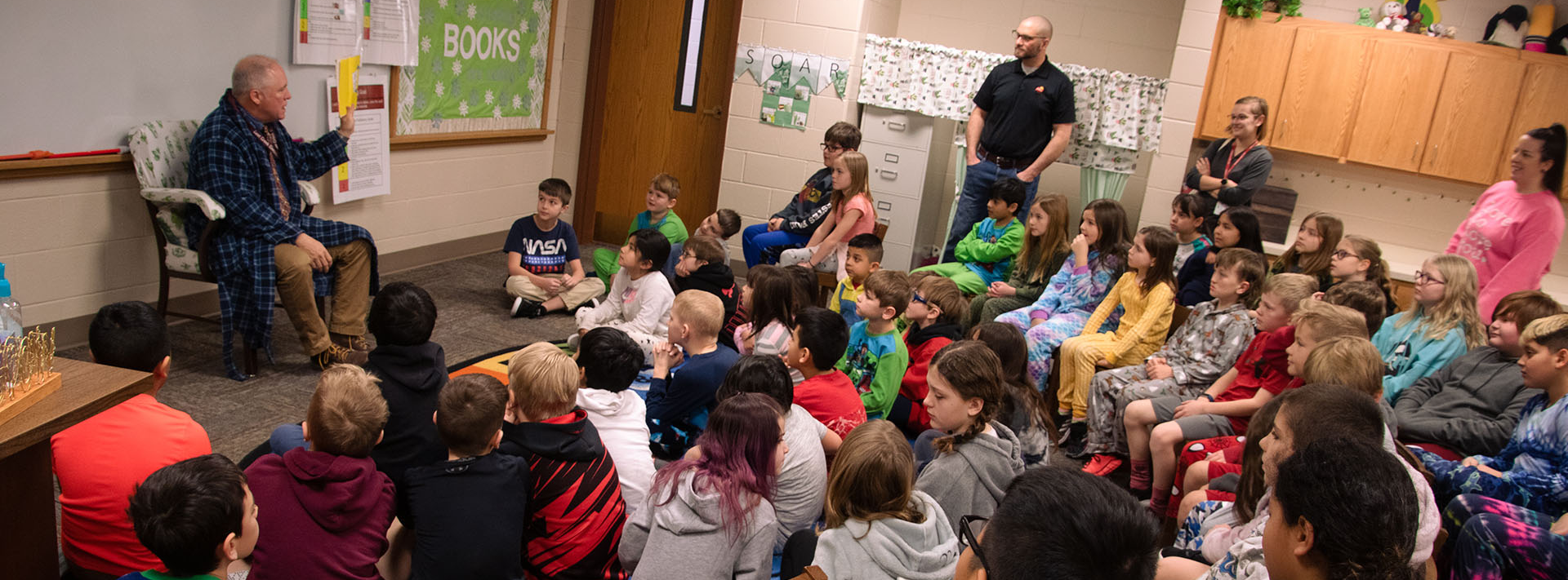 Man reading book to children in library