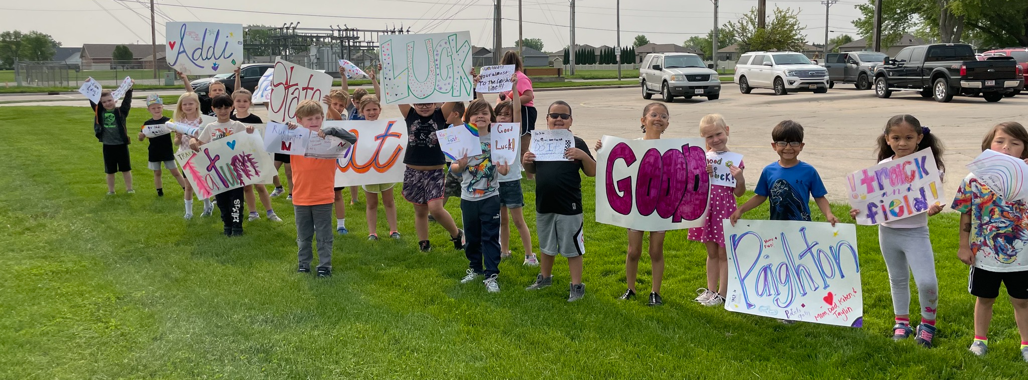 Lost Creek students hold signs and banners outside their school. The group is wishing the Columbus High School track members good luck at the state tournament.