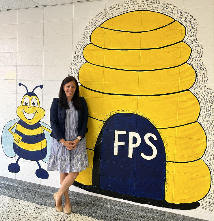 Image of principal Jennifer Stein in hallway with FPS bee and bee hive mural 