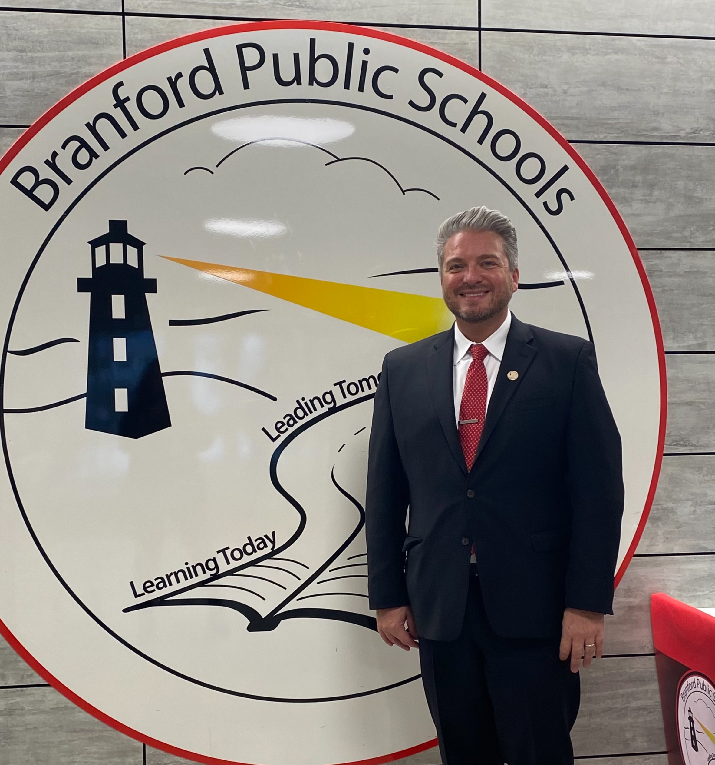 photo of superintendent Dr. Tranberg in front of Branford Schools logo