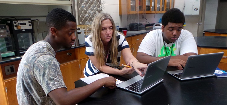 teacher and two students checking their laptops