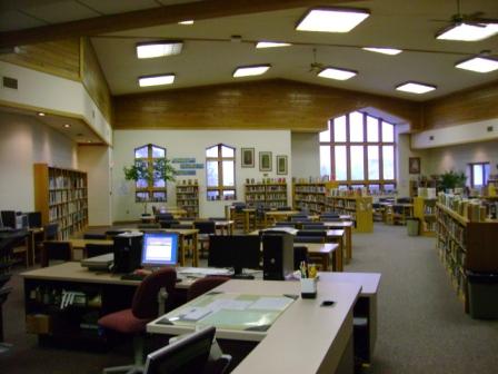 image of the inside of a library with windows and tables for seating