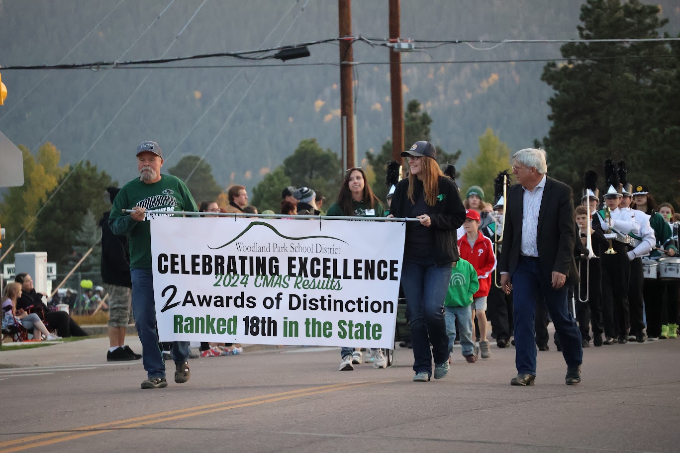 Members of Board of Education walking in the homecoming parade holding a banner