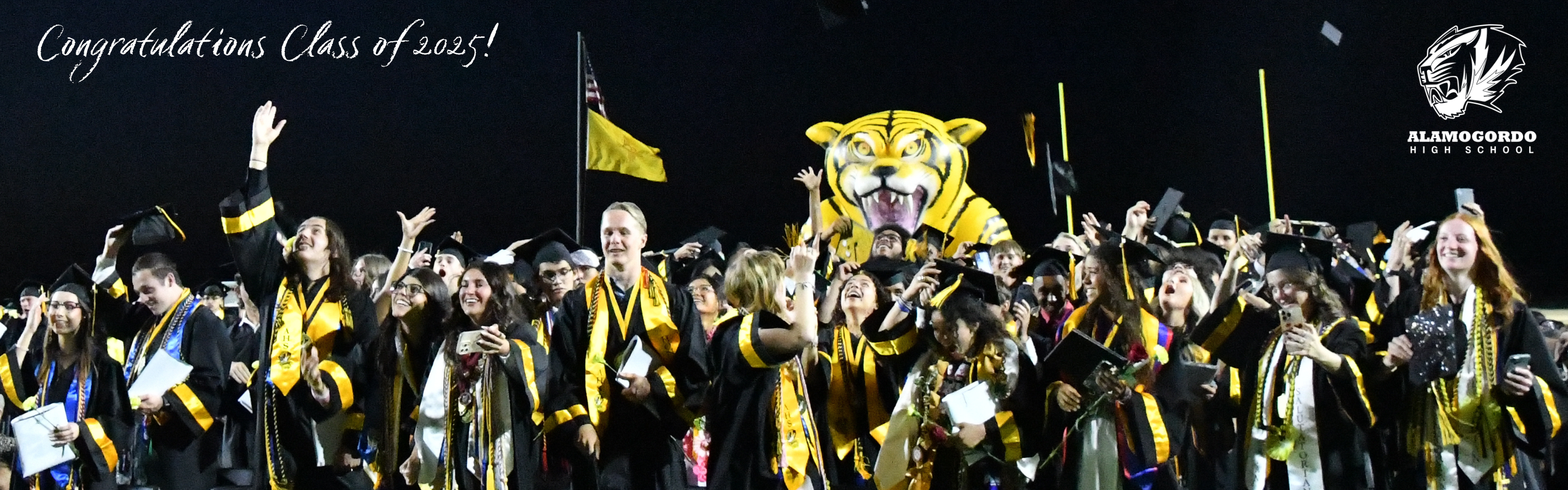 Alamogordo High School students in their caps and gowns throwing their caps into the aire at the end of the graduation ceremony