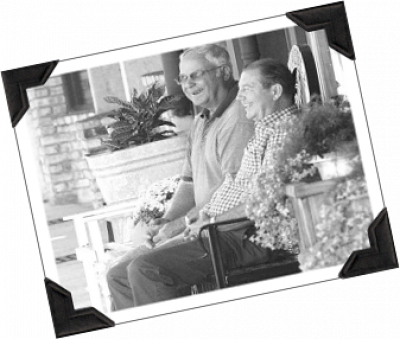 Old couple sitting on the porch smiling in black and white.