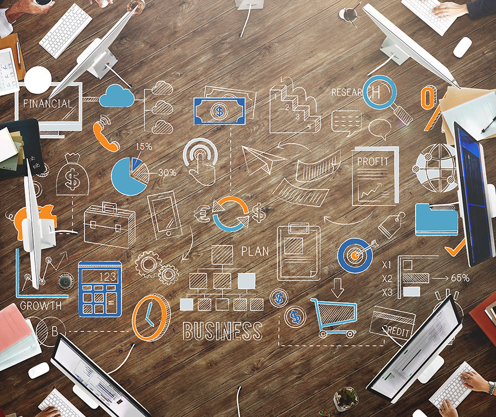 wooden desktop with sketches of business related terms and charts