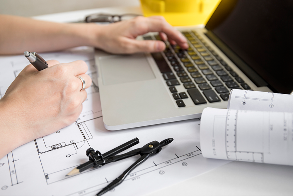 laptop with blueprints around it