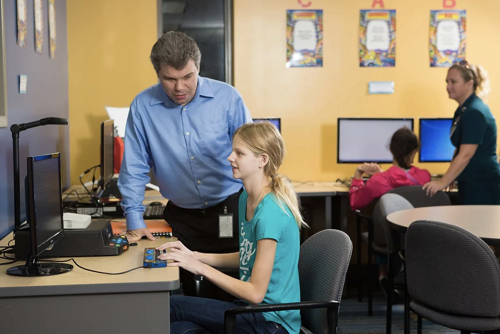 Student reading Braille with a teacher