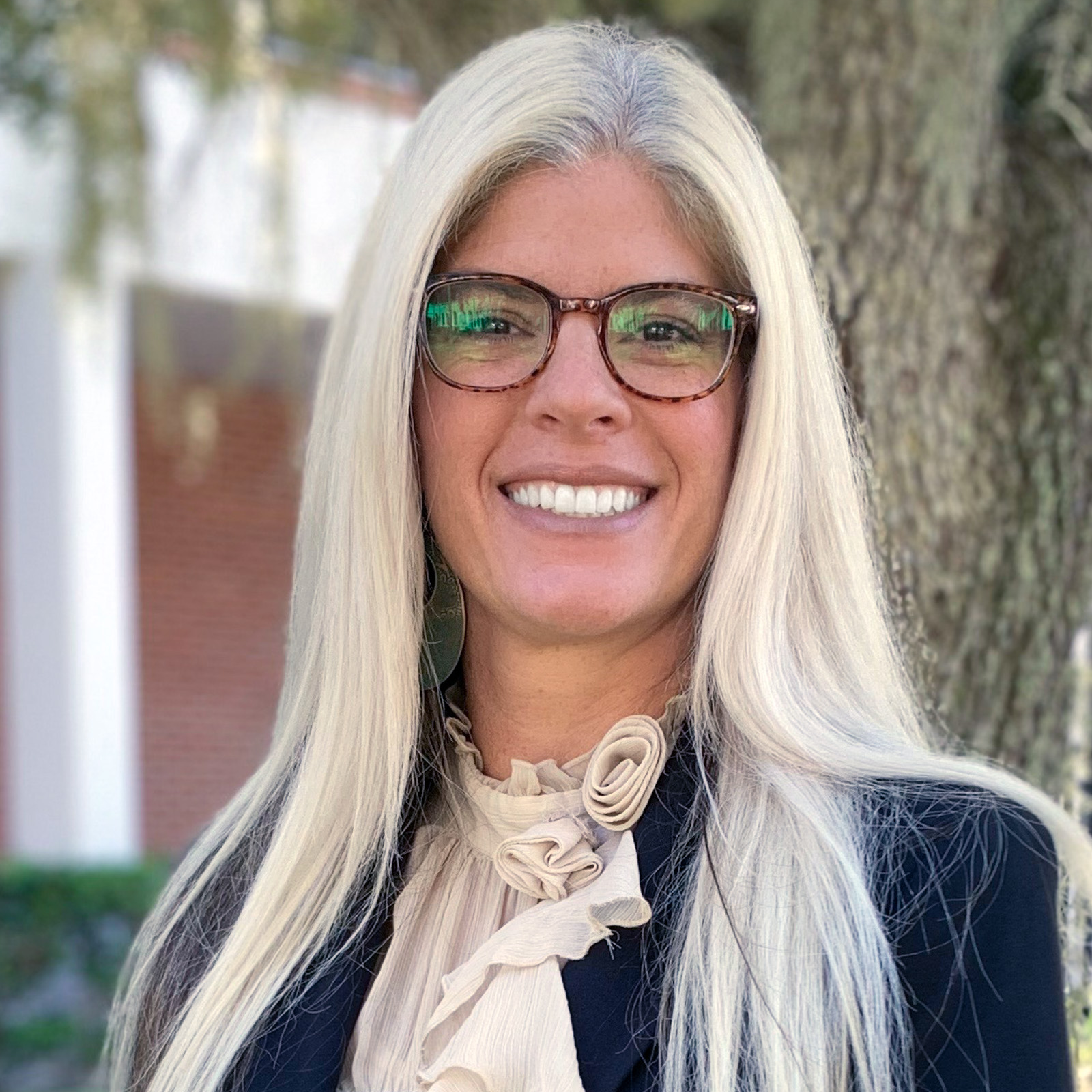 JuneAnn LeFors wearing glasses, beige blouse and navy blue jacket.