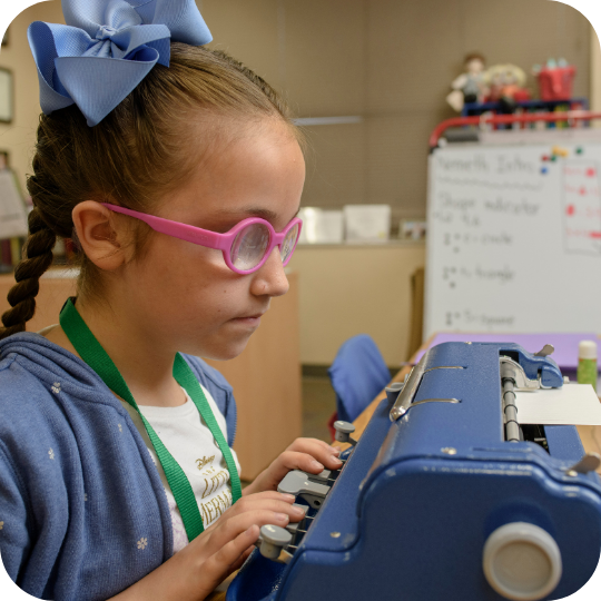 Blind girl typing on brailler.