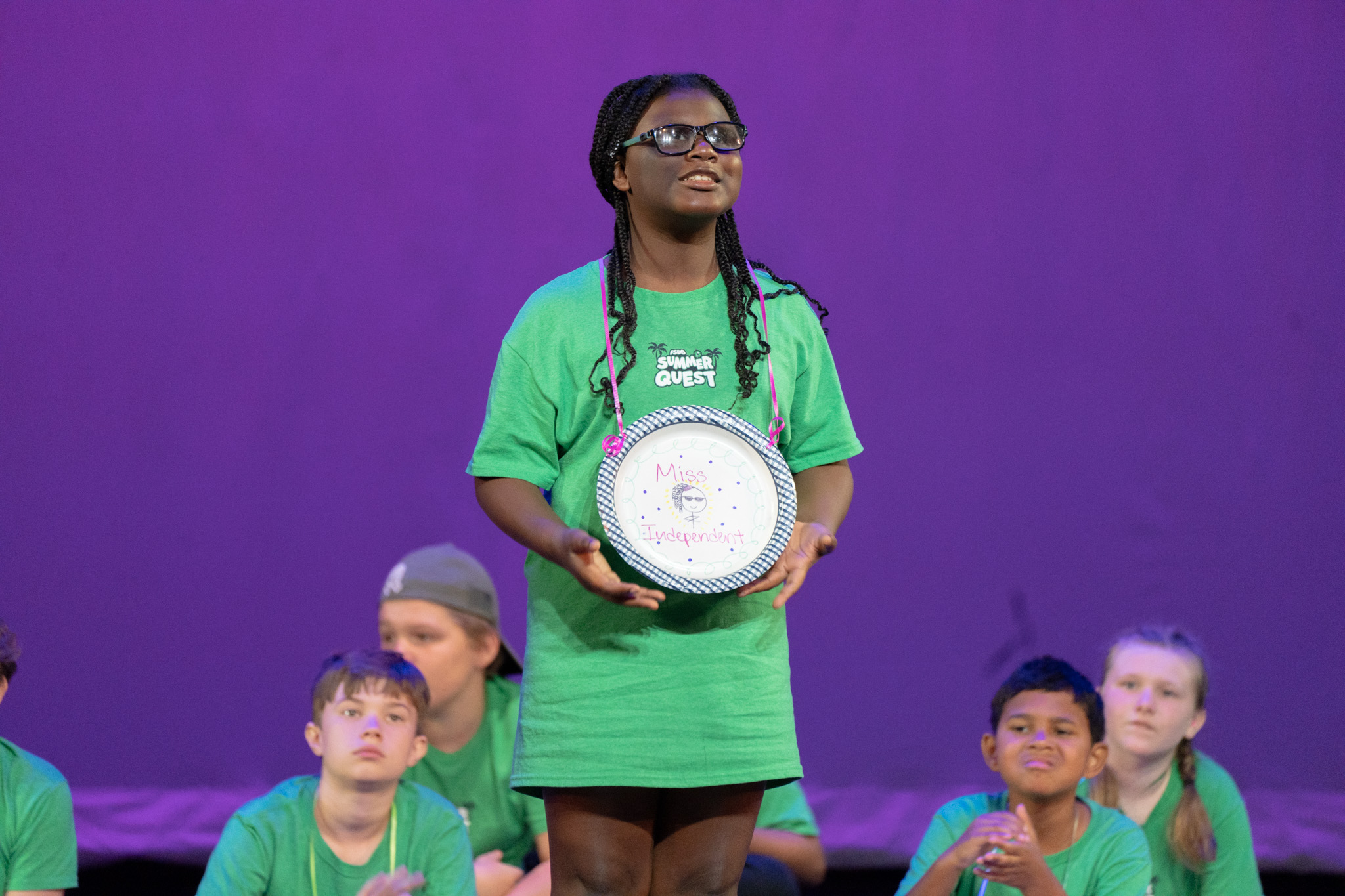 Visually Impaired girl holding a "plate" award on stage.