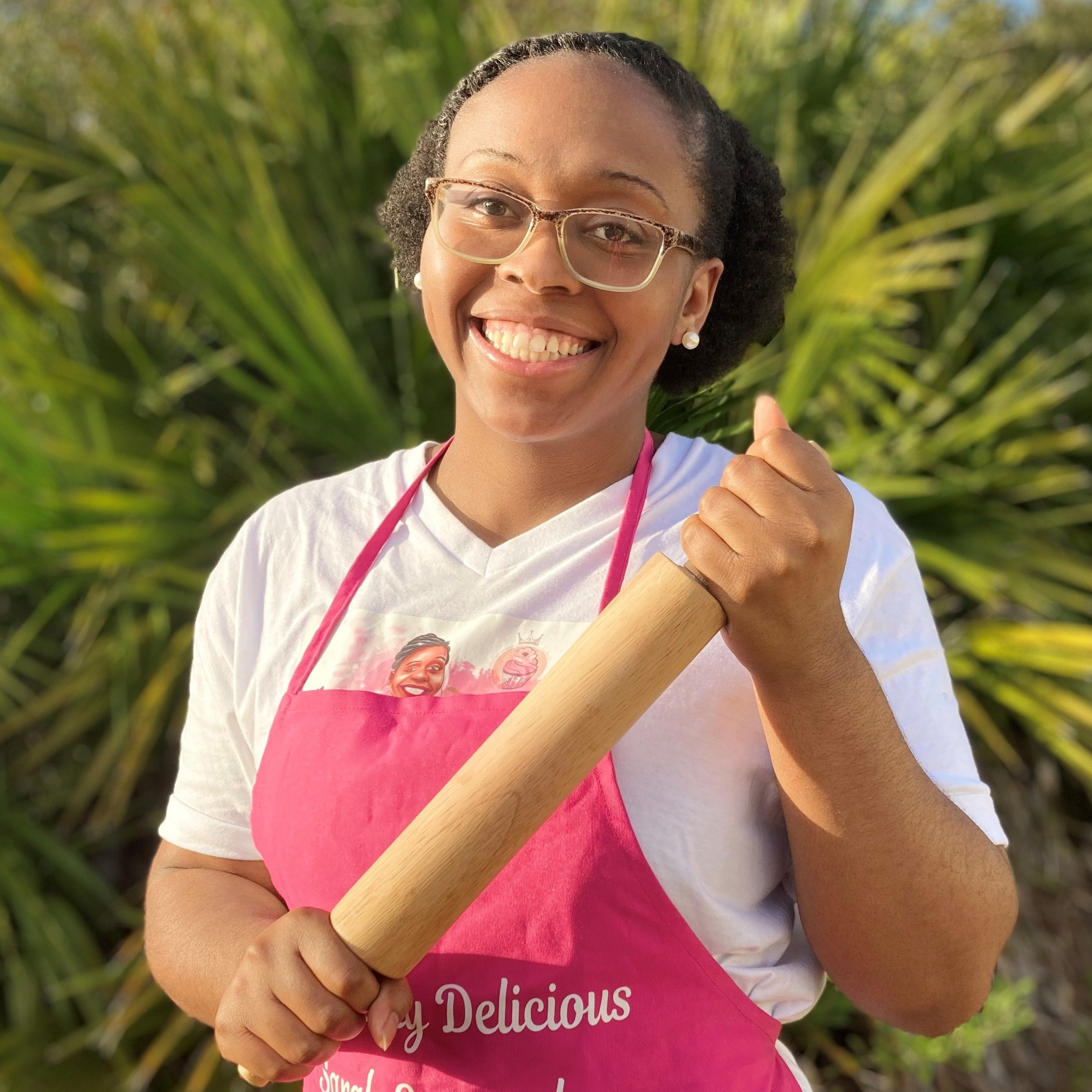 Sarah Emmanuel wearing a pink apron and holding a dough roller