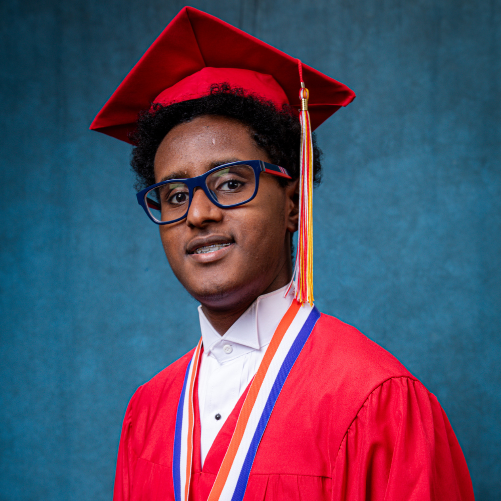 Tewdros Hammons wearing a red cap and gown.