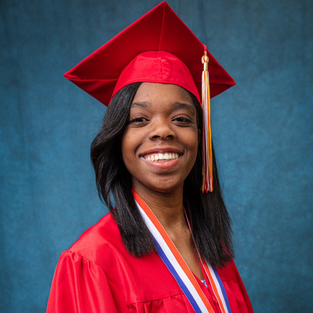 Raiyanah Robinson wearing a red cap and gown.