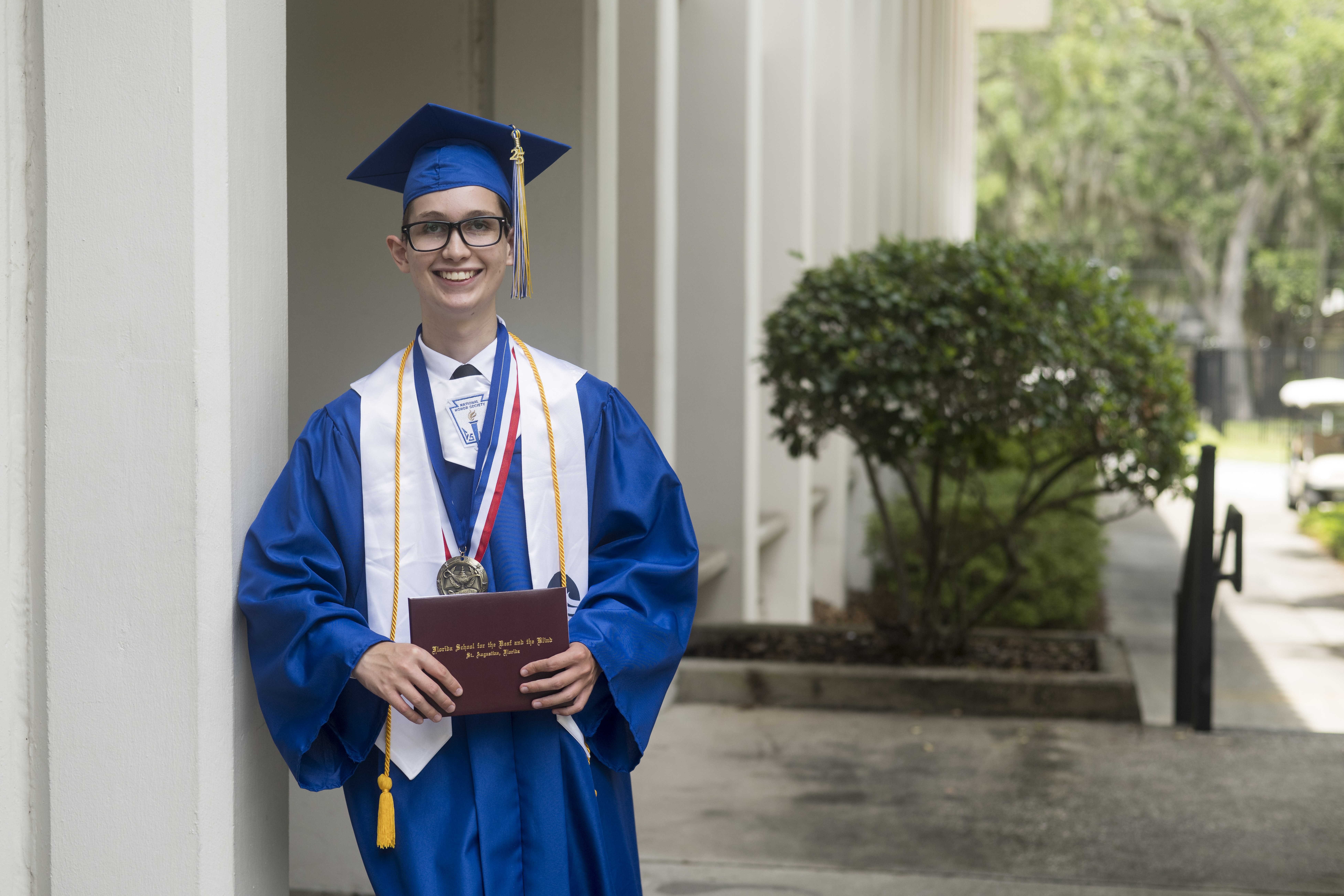 Logan Cake wearing a blue cap and gown.