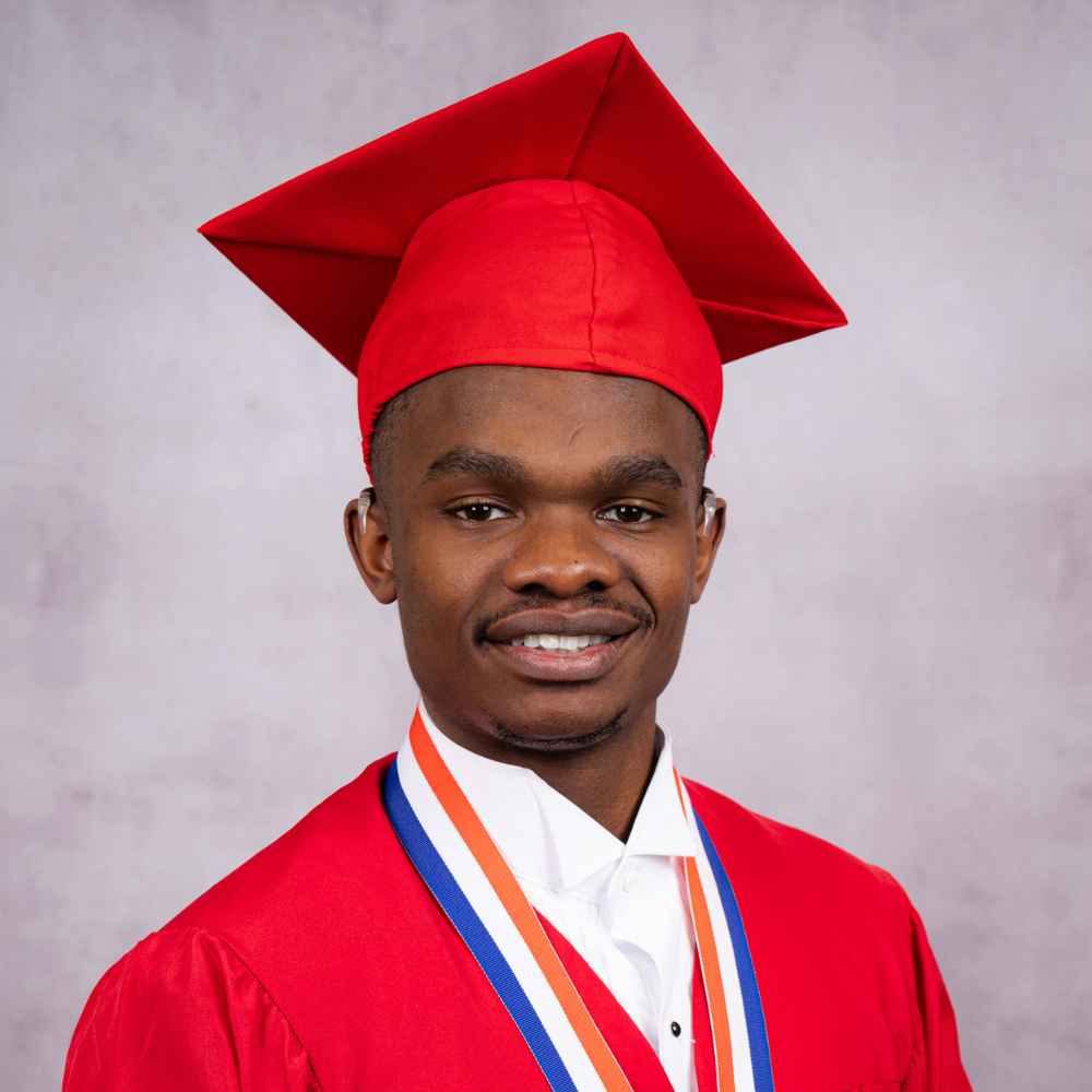 Frantz Valbrun wearing a red cap and gown.