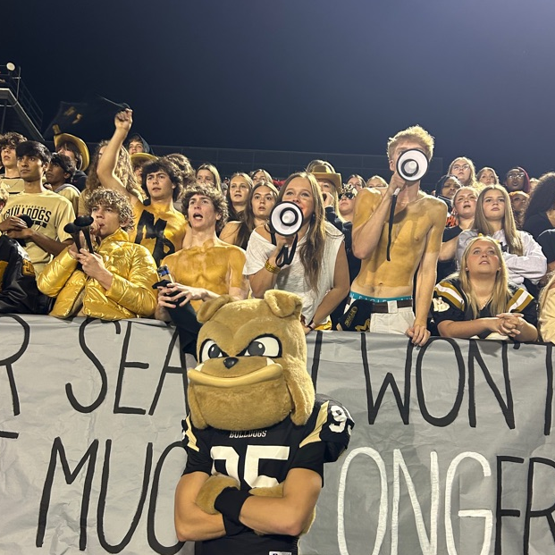 student section cheers at friday night football game with mascot