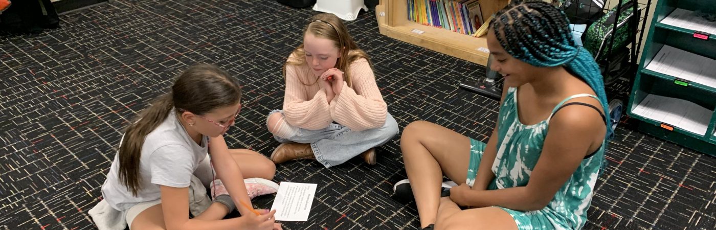 3 girls sitting on the floor talking to each other 