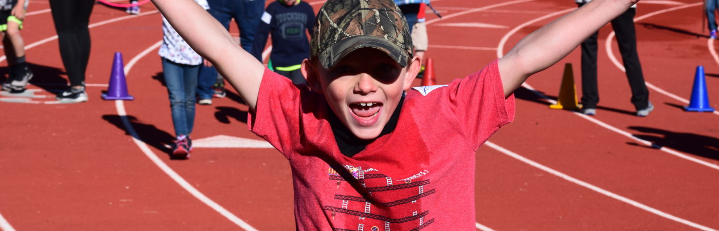 kid standing a the track holding his arms up