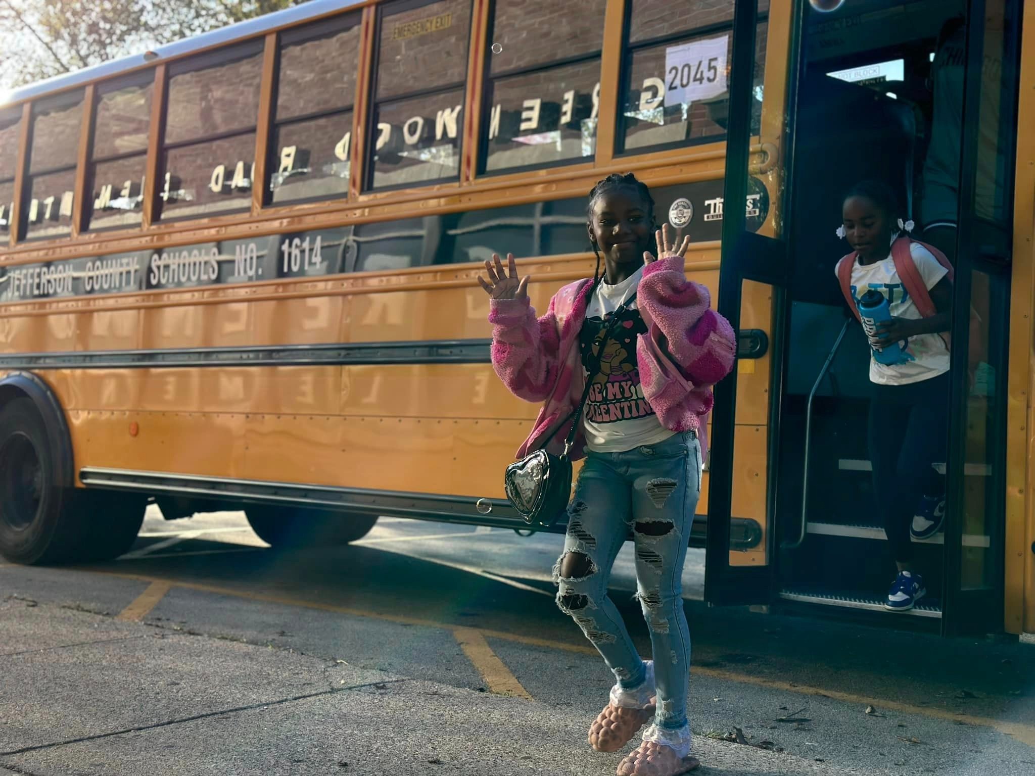 Girl waving getting off school bus