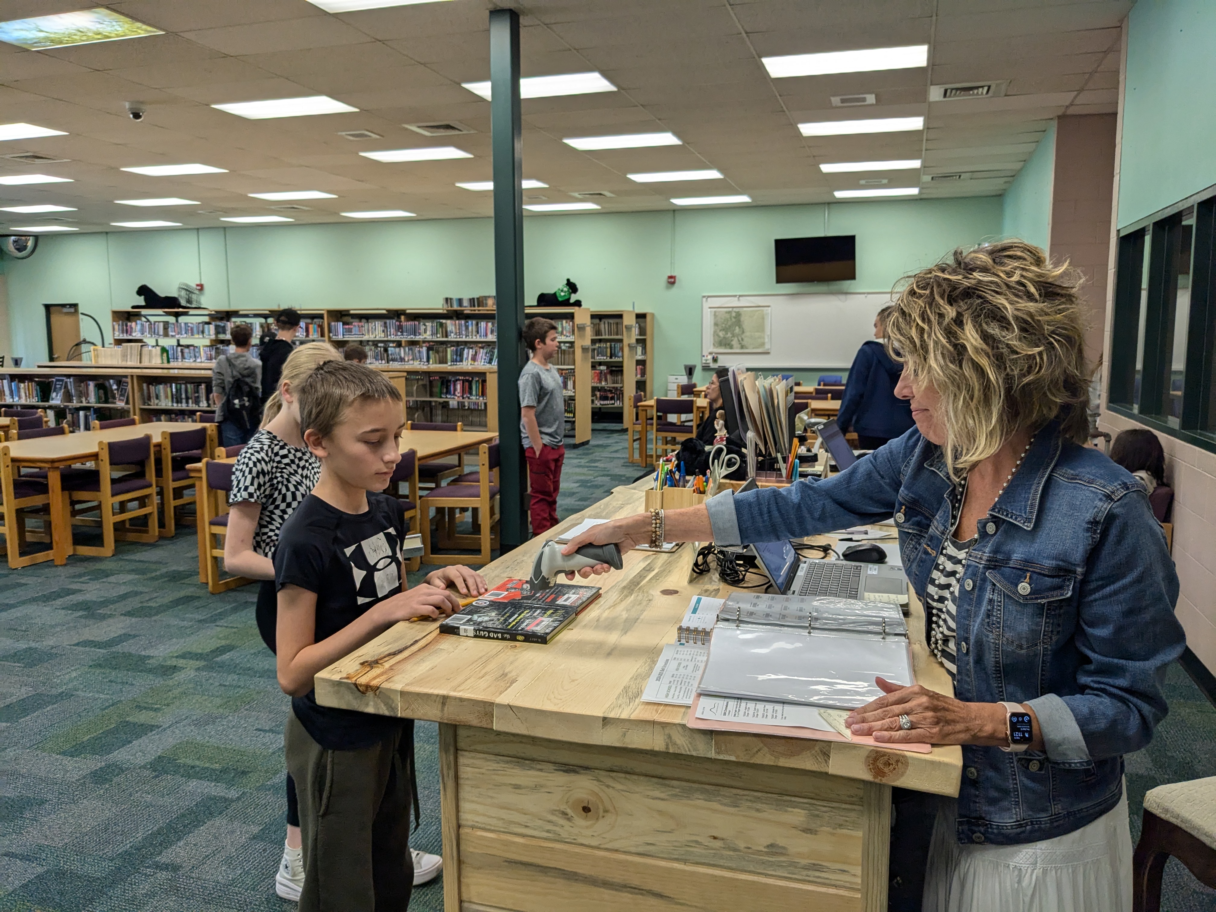 Ms. Pagett checking out a book to a student