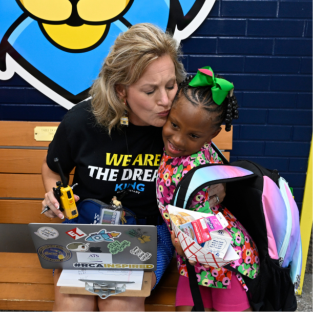 a person and young person sitting on a bench with a laptop