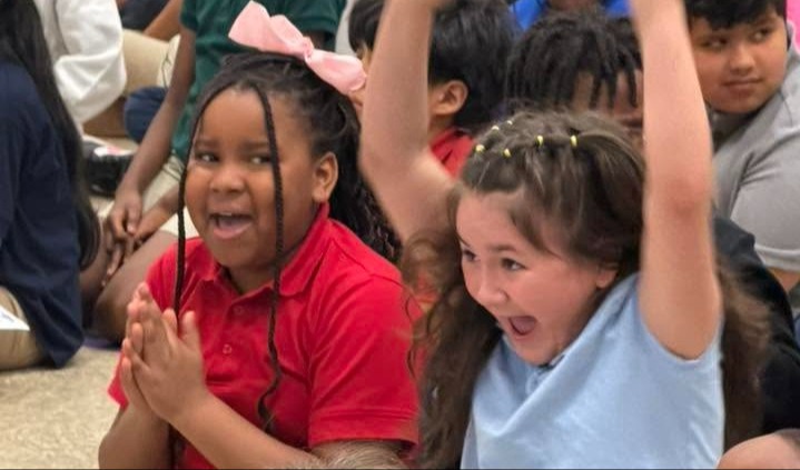 Students are clapping and cheering in excitement in a meeting. 